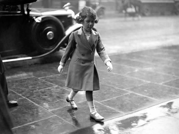 1932: Here, the young princess walks bareheaded through the rain on her arrival home.