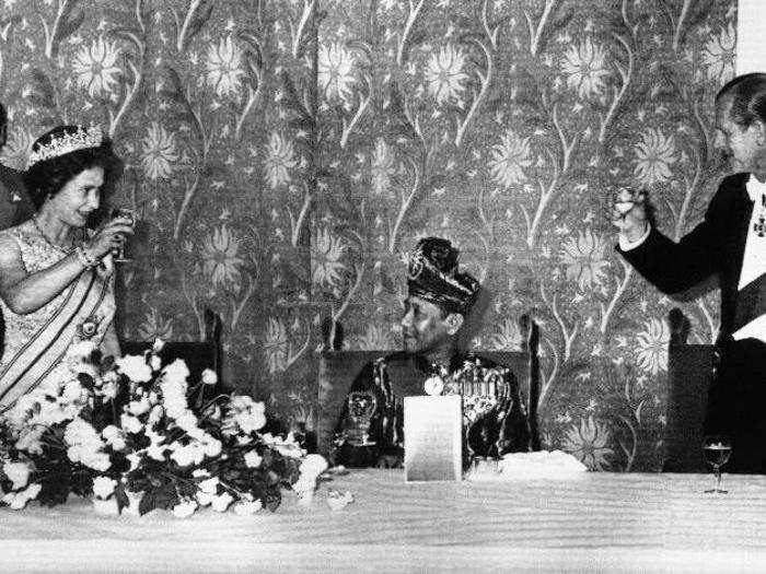 1974: Queen Elizabeth II of England and the Duke of Edinburgh toast the King of Malaysia, seated between them in evening on Thursday, July 12, 1974, at Claridges in London. The dinner marked the third day of the King and Queen of Malaysia’s visit to England.