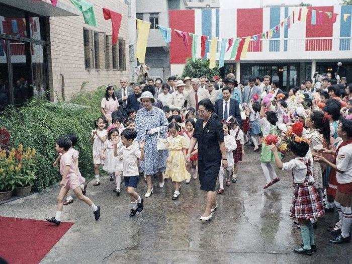 1986: Queen Elizabeth II is followed by joyous Chinese children as she tours a children