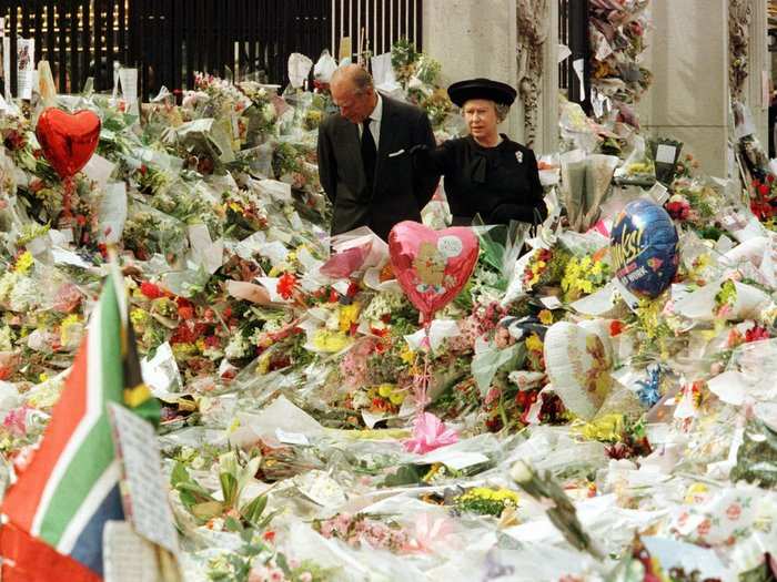 1997: Tragedy struck a year later also when Princess Diana was killed by injuries sustained in a car crash in Paris. This photo shows The queen and Prince Philip observing the vast sea of flowers left outside Buckingham Palace in the wake of Diana