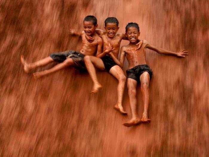 These boys converted a flooded rice field in Indonesia into a fun water slide.