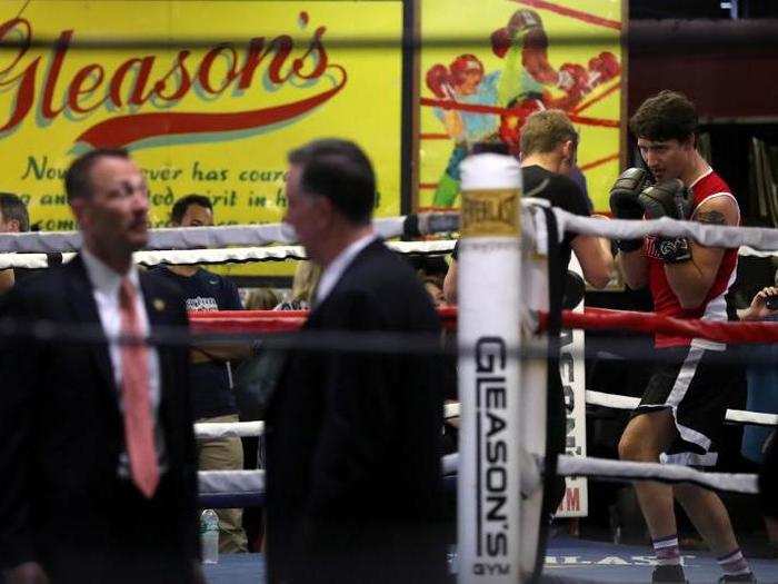 Secret service agents talk in the foreground as Justin Trudeau spars with Yuri Foreman in the ring at Gleason