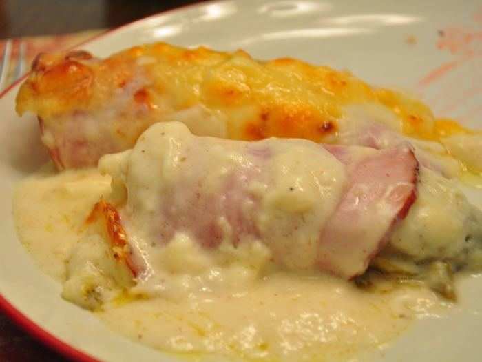 Chicons au gratin is a classic Belgian dish made of endives, rolled in ham, and bathed in Mornay sauce (béchamel with Gruyère cheese).  It