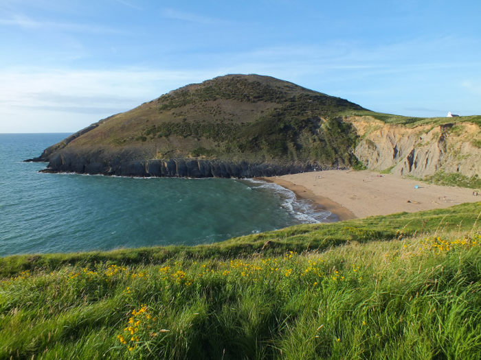 The sheltered cove of Mwnt, which is owned by the National Trust, is a popular off-the-beaten-track beach in Wales. Parking is available above the beach, with steps leading down to the tranquil setting. Plus, there