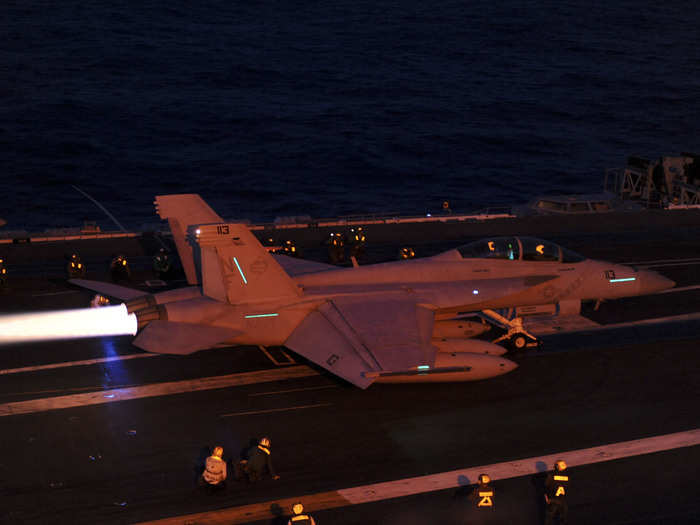 An F/A-18E Super Hornet from the Diamondbacks of Strike Fighter Squadron fires its afterburners before launching from the flight deck of the aircraft carrier USS George Washington.