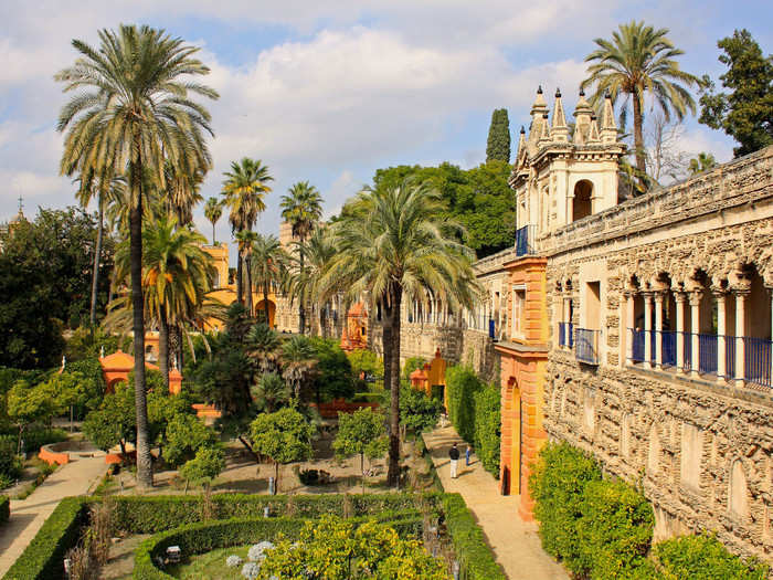 The Alcázar of Seville is a historic royal palace featuring lush gardens and detailed architecture.