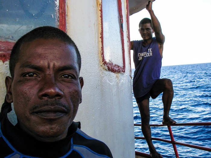 Two divers wait for their boat to be pulled from above. In the meantime, they pose for a photo.