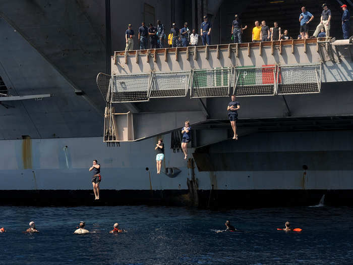 Sailors jump from the USS Dwight D. Eisenhower into the North Arabian Sea.