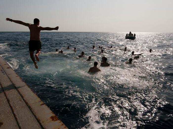 A sailor jumps off the stern gate of the USS New Orleans during a swim call in the Gulf of Aden.