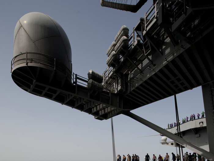 Sailors during a swim call jump off an aircraft elevator aboard the Nimitz-class aircraft carrier USS Carl Vinson into the Arabian Sea.