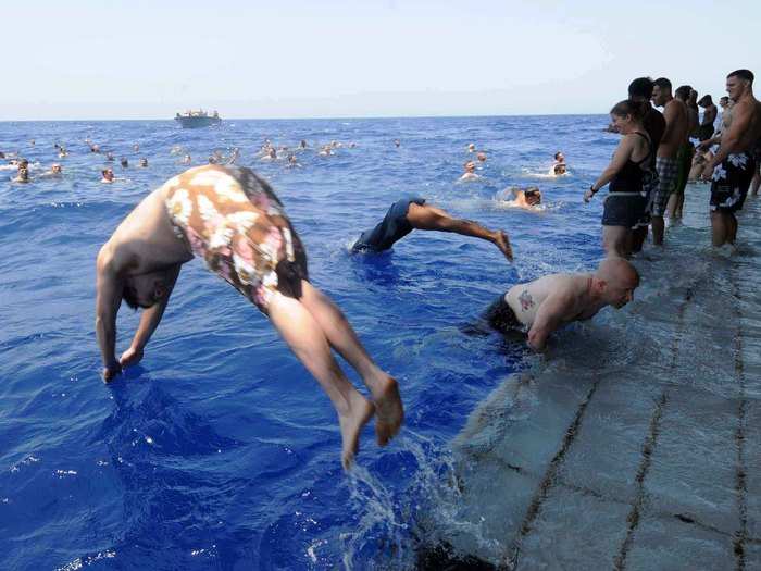 Sailors and Marines aboard the multipurpose amphibious-assault ship USS Bataan dive off the stern gate during a swim call in the Mediterranean Sea.