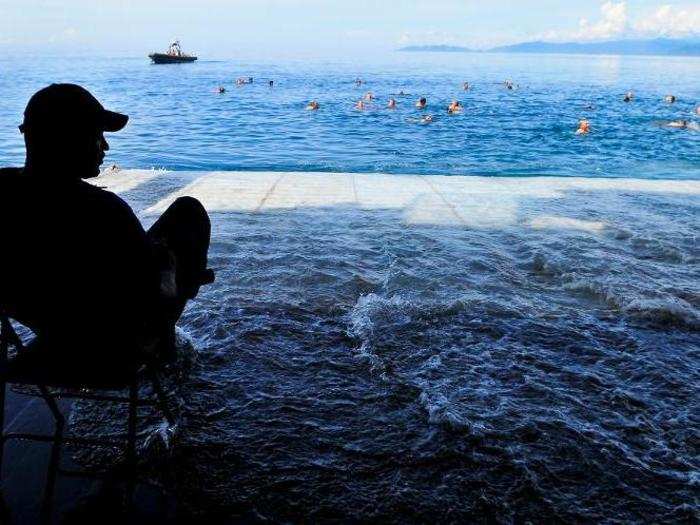 Military personnel watch as sailors from the USS Cleveland swim near Papua New Guinea.