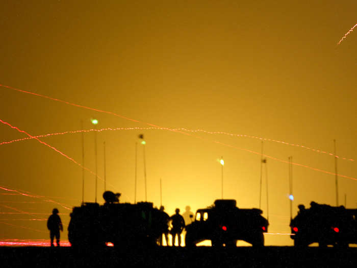 Members of US Army Task Force 3/15 watch as tracer fire and flares light the sky, during a night live fire assault exercise in the northern Kuwaiti desert, December 9, 2002.