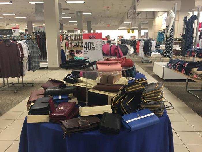 Purses are piled on display tables.