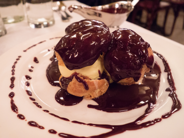 Profiteroles are little puff pastries filled with vanilla ice cream and topped with velvety chocolate sauce.