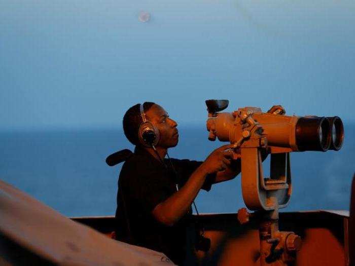 A sailor uses binoculars at sundown from the bridge of the USS Harry S. Truman aircraft carrier in the eastern Mediterranean Sea June 13, 2016.