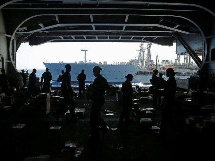 US Navy sailors sort mail in the hangar on the USS Harry S. Truman aircraft carrier in the eastern Mediterranean Sea June 15, 2016.