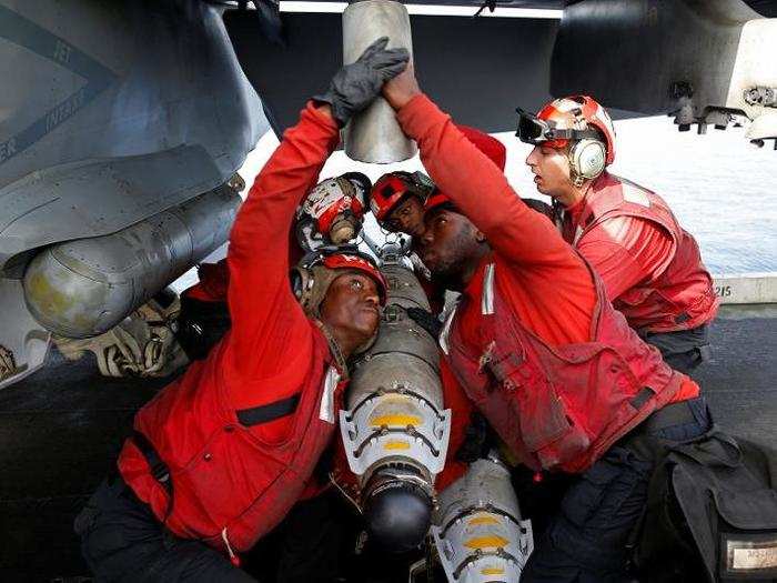 US Navy sailors attach ammunition to a F/A-18 fighter jet before a mission on the flight deck of the USS Harry S. Truman aircraft carrier in the eastern Mediterranean Sea June 14, 2016.