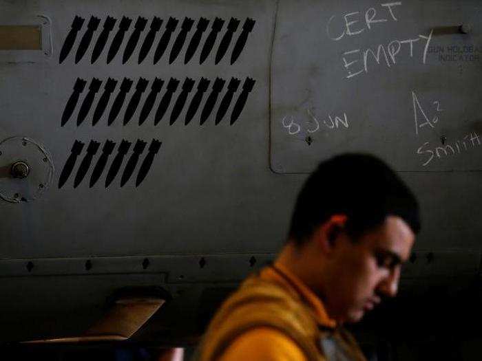 A sailor walks by an F/A-18 fighter jet in a hangar on the USS Harry S. Truman aircraft carrier in the eastern Mediterranean Sea June 13, 2016.