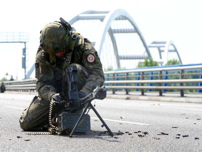 A Polish soldier reloads his weapon while securing a bridge.