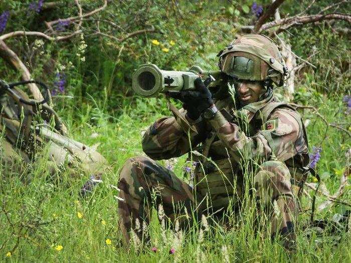 A French paratrooper aims his antitank weapon at an enemy tank.