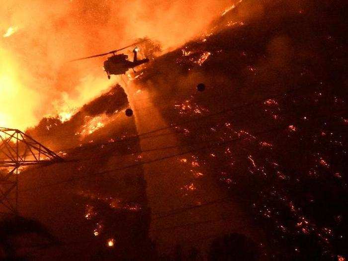 A Los Angeles County fire helicopter makes a night drop while battling the so-called 