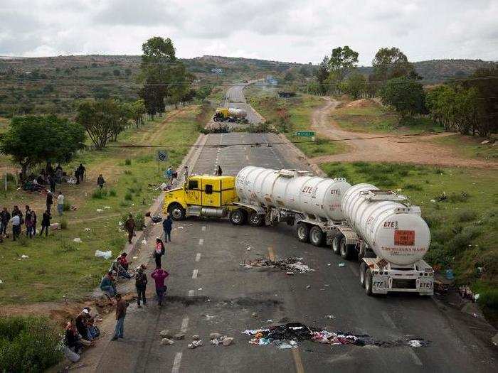 Protesters stand beside trucks blocking the highway in the state of Oaxaca, Mexico. The teachers are protesting against plans to overhaul the country