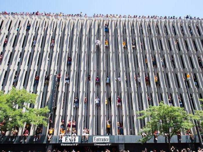 Fans scale the side of a parking garage to get a better view during the Cleveland Cavaliers 2016 championship victory parade and rally on June 22, 2016 in Cleveland, Ohio.