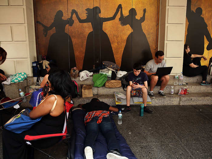 People, many who have been there for days, wait in line with dozens of others for tickets for the popular Broadway show 