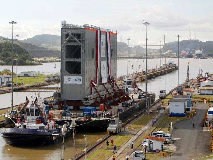 The first rolling gate for the new locks on the Pacific side of the Panama Canal is transported on a barge with the help of two tugboats.