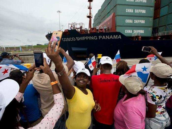 A woman takes a selfie as a cargo ship crosses the new Agua Clara locks, part of the Panama Canal expansion project.