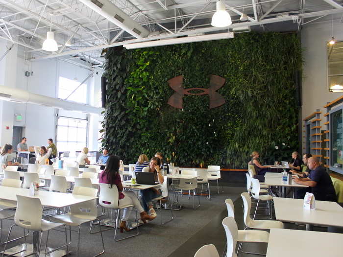 One of the largest areas in the building is the "Humble and Hungry café," where employees can buy sandwiches, pizza, salads, and smoothies. The main wall features living leaves and vines.