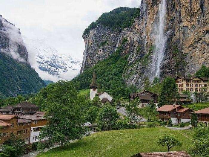 The Staubbach waterfall in Switzerland sits next to the houses and church of a local town, covering it in a mist of spray.