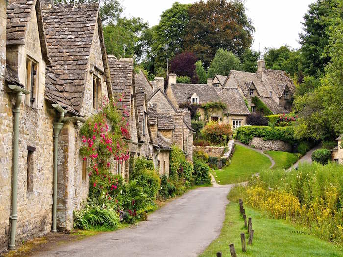 Stroll along Arlington Row, a scenic stretch of cottages that were built in 1380 in the village of Bibury in the Cotswolds, UK.