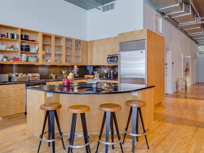 The open kitchen with black granite countertops has a functional island and bar stool seating.