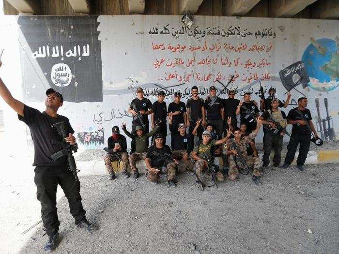 Here, security forces posed for a photo in front of murals ISIS had painted with themes of violence.