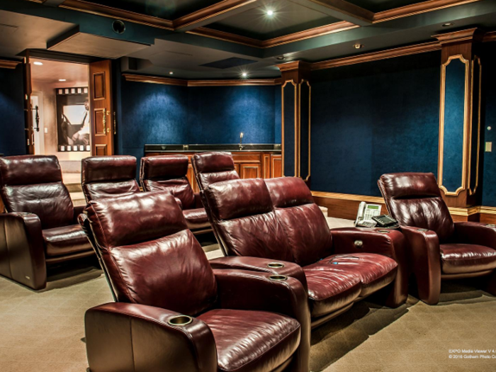 This luxurious home theater with blue velvet walls comfortably seats eight people in leather reclining chairs.