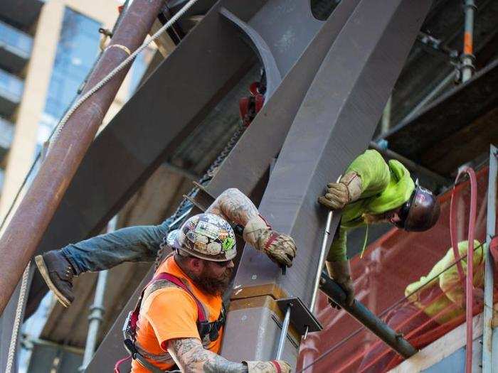 A construction crew is building the three glass spheres (the largest measuring 90 feet tall) that will connect to form one giant space.