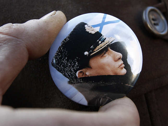 Putin is adored back home. He has a tough, heroic image, which is why he is often pictured, like in this badge, in macho poses wearing military uniform.