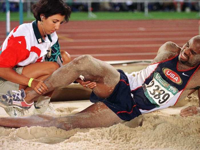 An aide attends to Mike Powell after he injured himself on his final attempt to win gold in the long jump at the Atlanta Games.