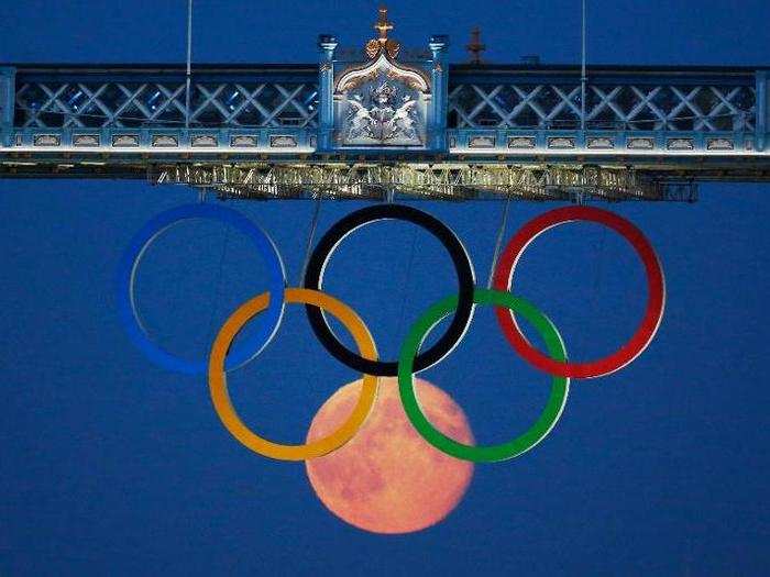 The moon is perfectly positioned behind the Olympic logo hanging from the Tower Bridge in 2012.