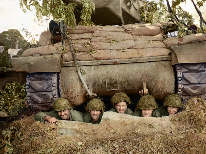 The crew of the US Army 703rd Tank Destroyer Battalion of the 3rd Armored Division pose underneath their tank near the French town of Marigny.