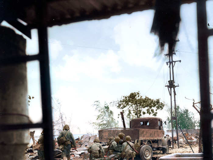 A view from a broken window of US Marines firing at Japanese soldiers hiding behind debris in Saipan in 1944.