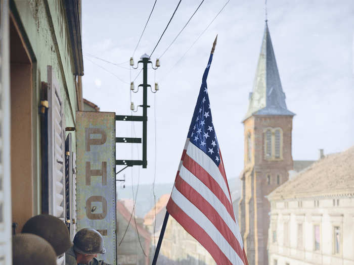 In this iconic photo, Captain Thomas Garahan of Easy Company, 2nd Battalion, 398th Infantry Regiment, 100th Infantry Division raises an American flag that was secretly made by a local French girl from a store in Bitche, France. The infantry division was later referred to as the "Sons of Bitche," after liberating the region in March 1945.