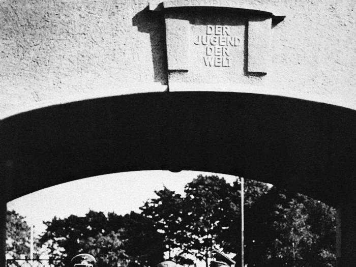 Here we see Hitler, center, and two aides entering the Olympic Village for an inspection. The gateway inscription reads, "To the Youth of the World."