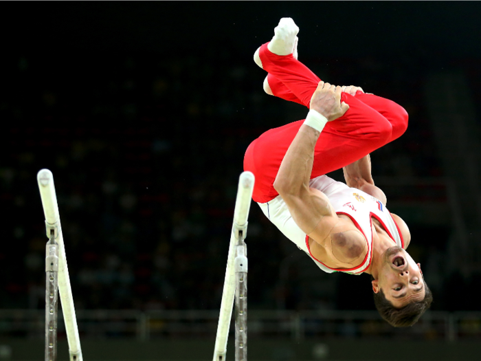 Russian gymnast Nikolai Kuksenkov flips off of the parallel bars.