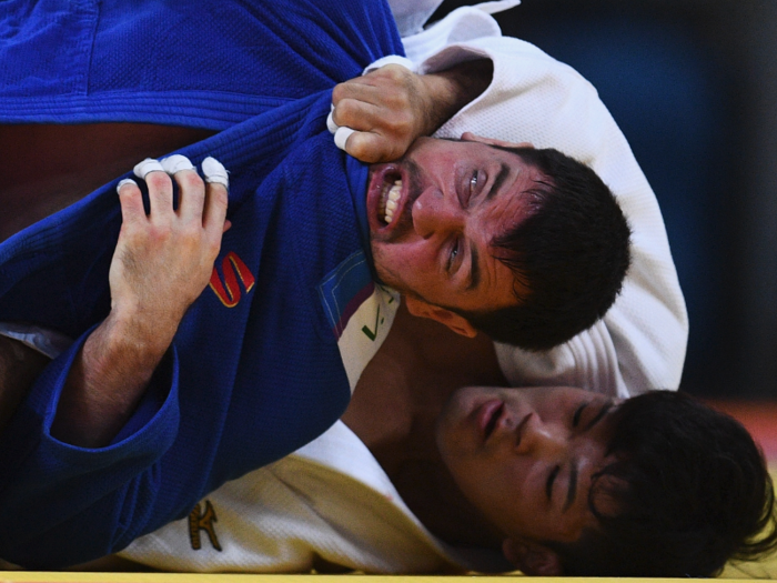 Victor Scvortov of United Arab Emirates (in blue) fights Shohei Ono of Japan in men