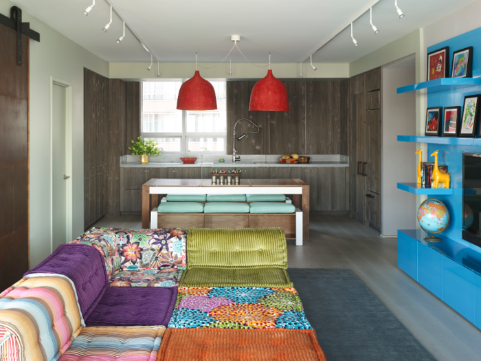 By adding pops of bold color — red hanging light fixtures, a multicolored sofa, and turquoise seat cushions — Incorporated Architecture & Design decorators completely revived the room.