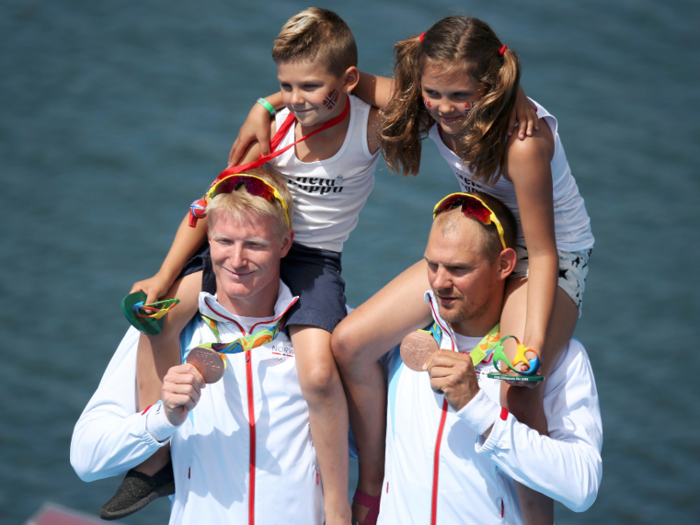 Norwegian rowers Kjetil Borch and Olaf Tufte pose with their children on their shoulders after winning bronze.