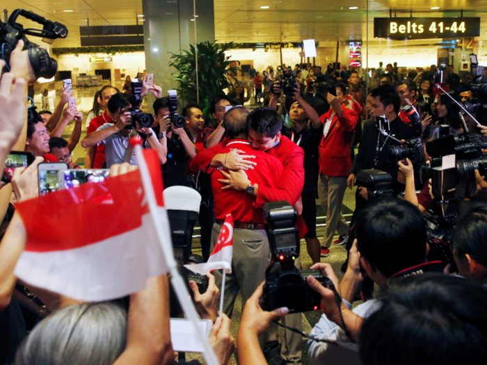 Swimmer Joseph Schooling gets a warm welcome home, hugging his father after arriving at Singapore